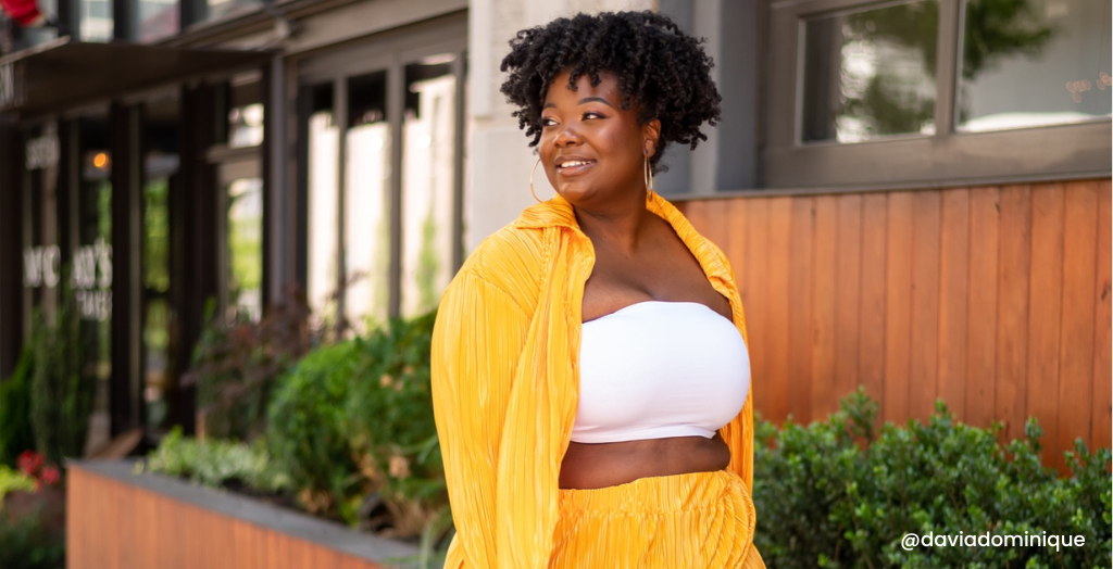 Creator @daviadominique smiles for a photo in a yellow, flowy two-piece outfit paired with a white crop top