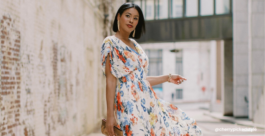 Creator @cherrypickedstyle wearing flowy cream colored blouse, posing for photo