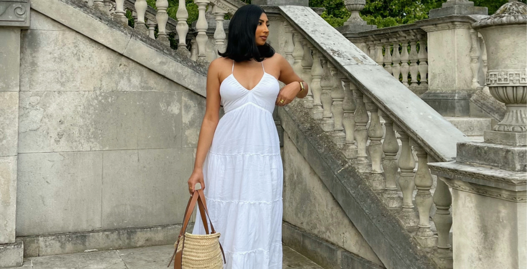Creator in white flowy dress posing for photo in front of concrete stairs