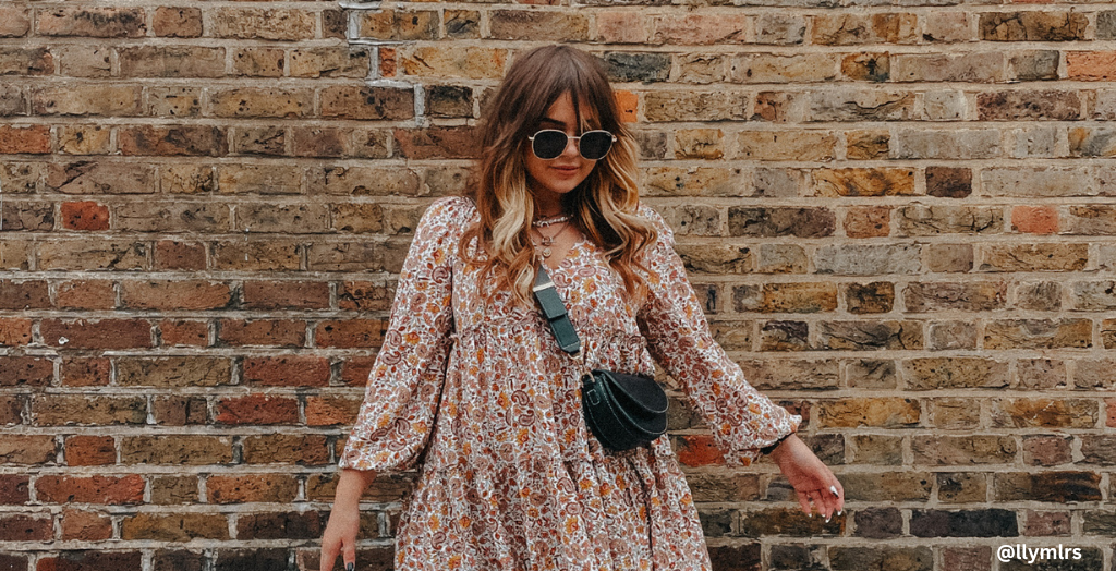 Creator @llymlrs posing for photo in front of break wall with a black over the shoulder purse