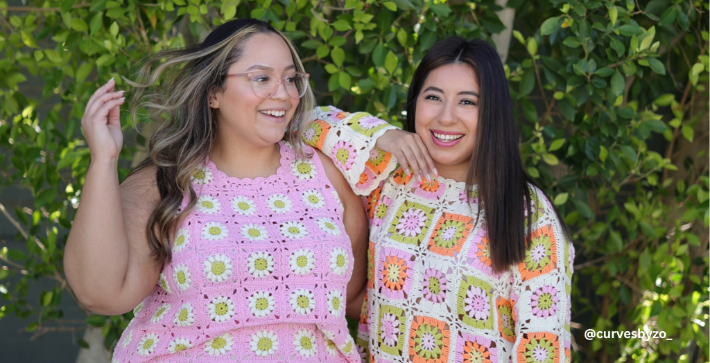 Content creator @curvesbyzo_ smiling for a photo with another content creator in front of a tree