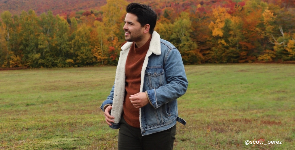 Content creator @scott_perez in a denim jacket in a field with colorful autumn trees in the background.