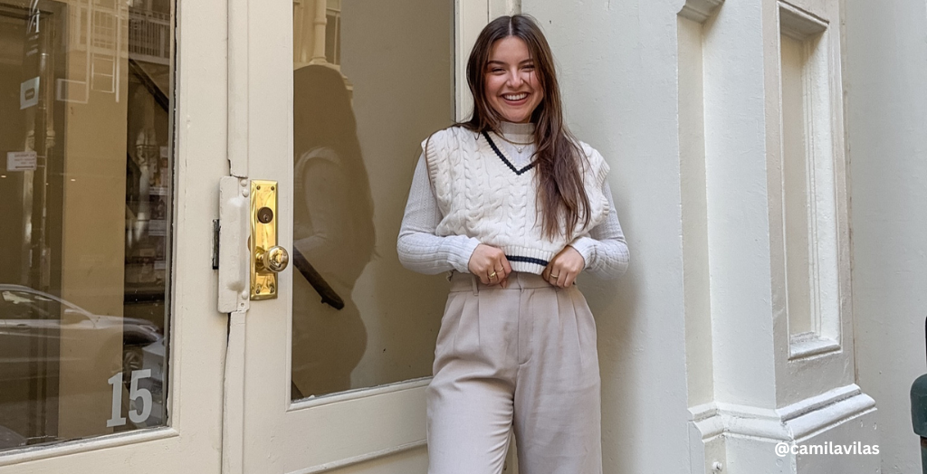 Content creator @camilavilas smiles in front of the glass panel door while wearing a cream monochromatic outfit